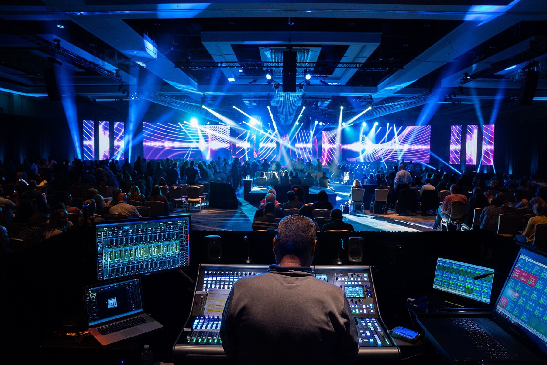 A live general session in progress, audience and stage lighting viewed from the production desk